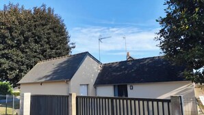 A single-story house with a dark roof, a gated driveway, and a satellite dish on the roof. - Gîte Le Magnolia (Ploërmel)