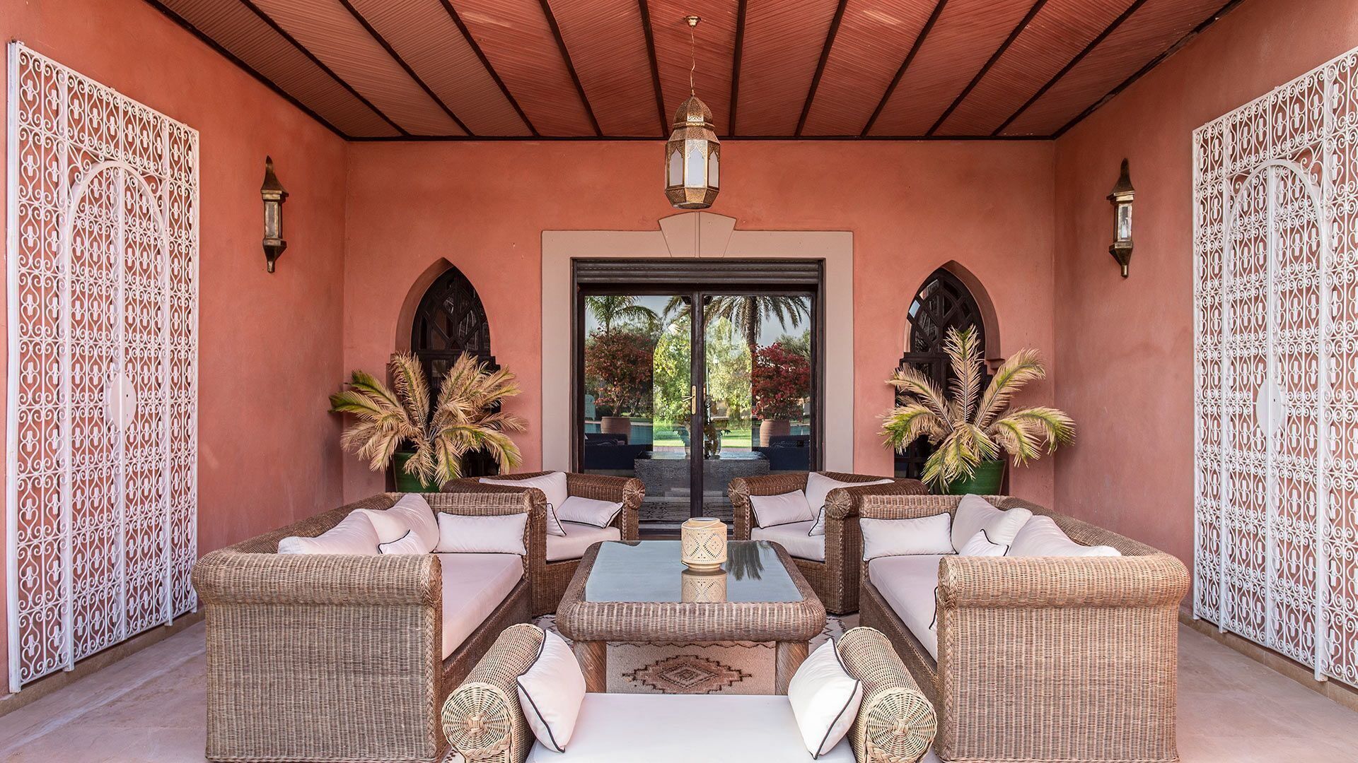 A covered patio with wicker furniture, a glass-top coffee table, and decorative lanterns.