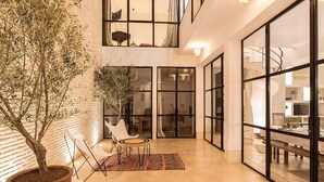 A spacious indoor area with a potted tree, a small round table, and a patterned rug. - My Rental Homes | Riad Special with two courtyards and  swimmingpool (Marrakesh)