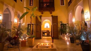 A spacious atrium with a central fountain, surrounded by potted plants and seating areas.