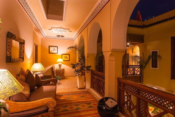 A warmly lit hallway with a sofa, lamps, and a decorative ceiling. - My Rental Homes - Riad Ikram with roof terrace and pool (Marrakesh)