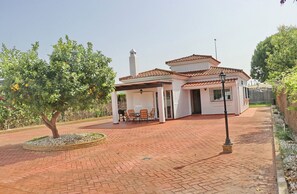 Une maison à deux étages avec un patio, un arbre et un petit jardin.