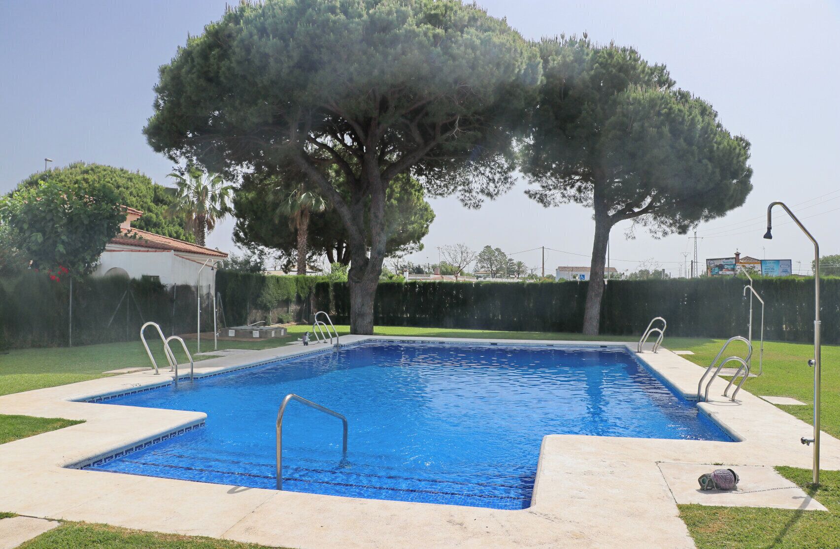 Une piscine rectangulaire à l’eau d’un bleu limpide, entourée d’une terrasse en béton.