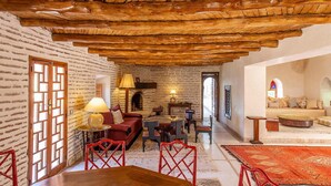 A cozy interior with exposed wooden beams, a brick wall, and a traditional fireplace. - My Rental Homes - Villa Royale with pool and garden (Marrakesh)
