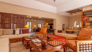 A spacious living room with a fireplace, wooden furniture, and a bookshelf. - My Rental Homes - Villa Royale with pool and garden (Marrakesh)