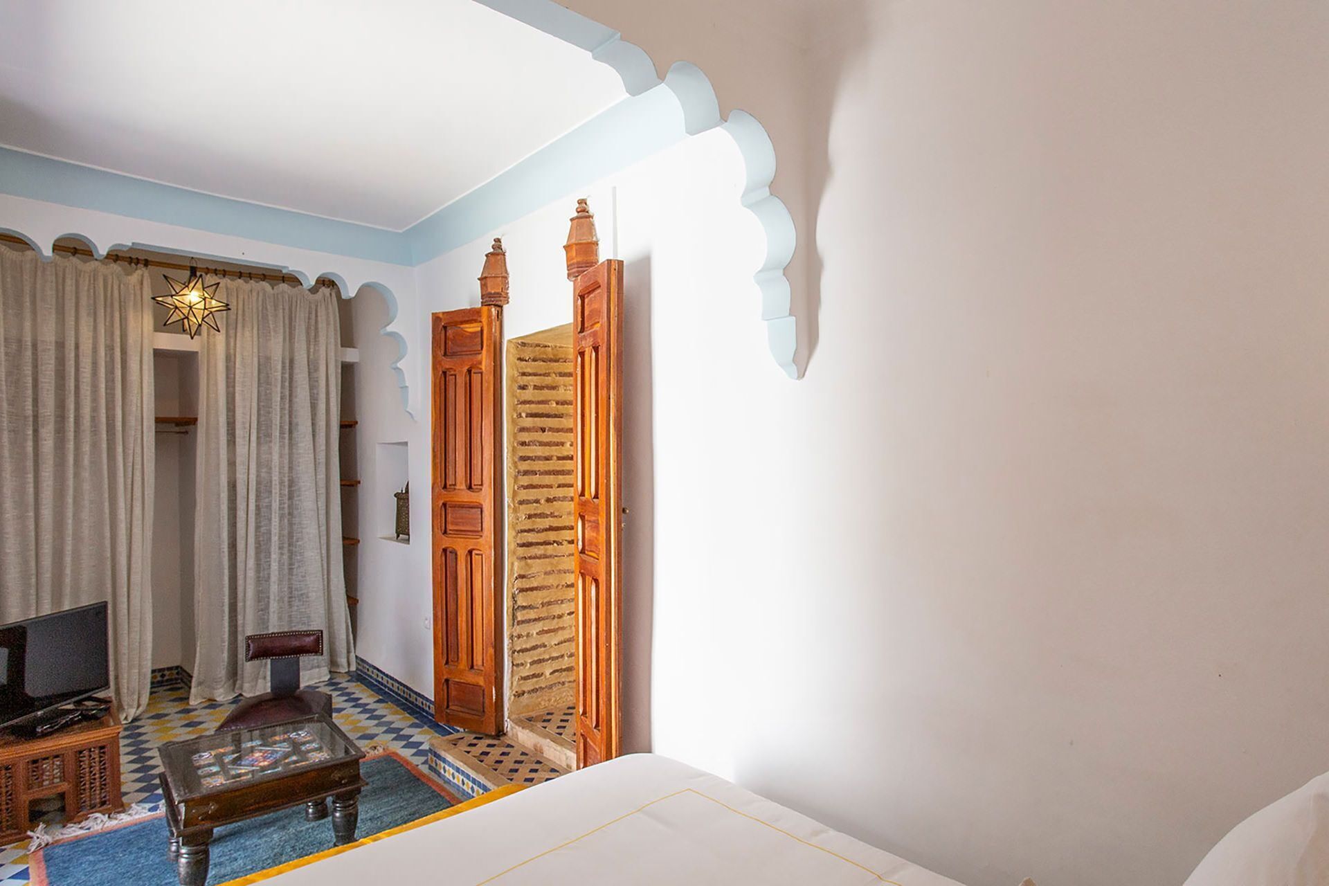 Ein Hotelzimmer mit Bett, Fernseher, einem kleinen Tisch und einer dekorativen Sternleuchte.
