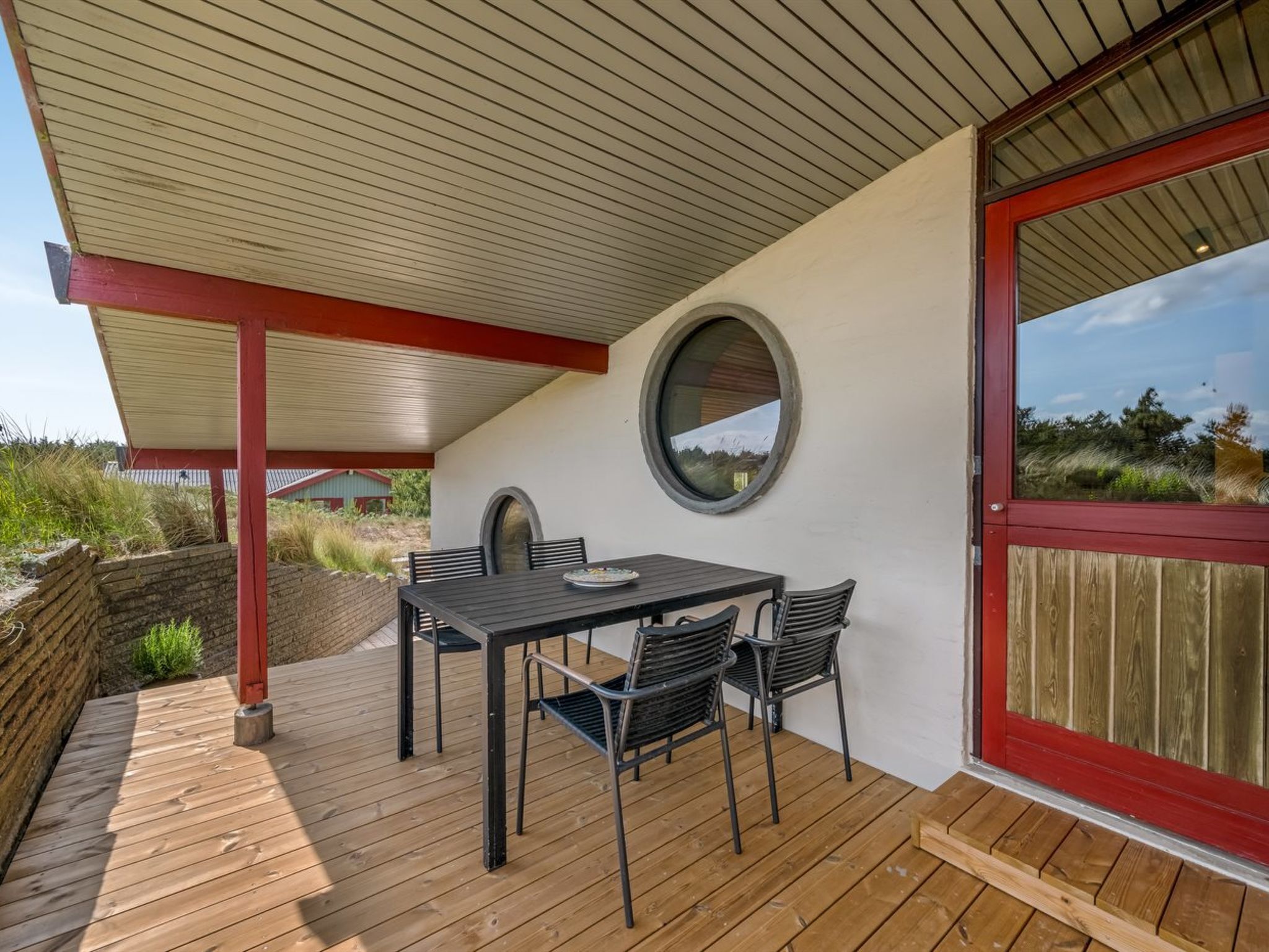 Une terrasse couverte avec une table et des chaises, une terrasse en bois et une vue sur le paysage.