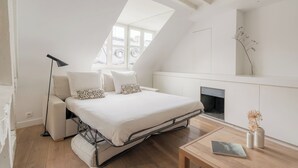 A modern bedroom with a loft bed, a bedside table, a lamp, and a fireplace.