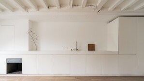 A minimalist room with a wooden floor, white walls, and a built-in shelf with a vase and a small wooden box.