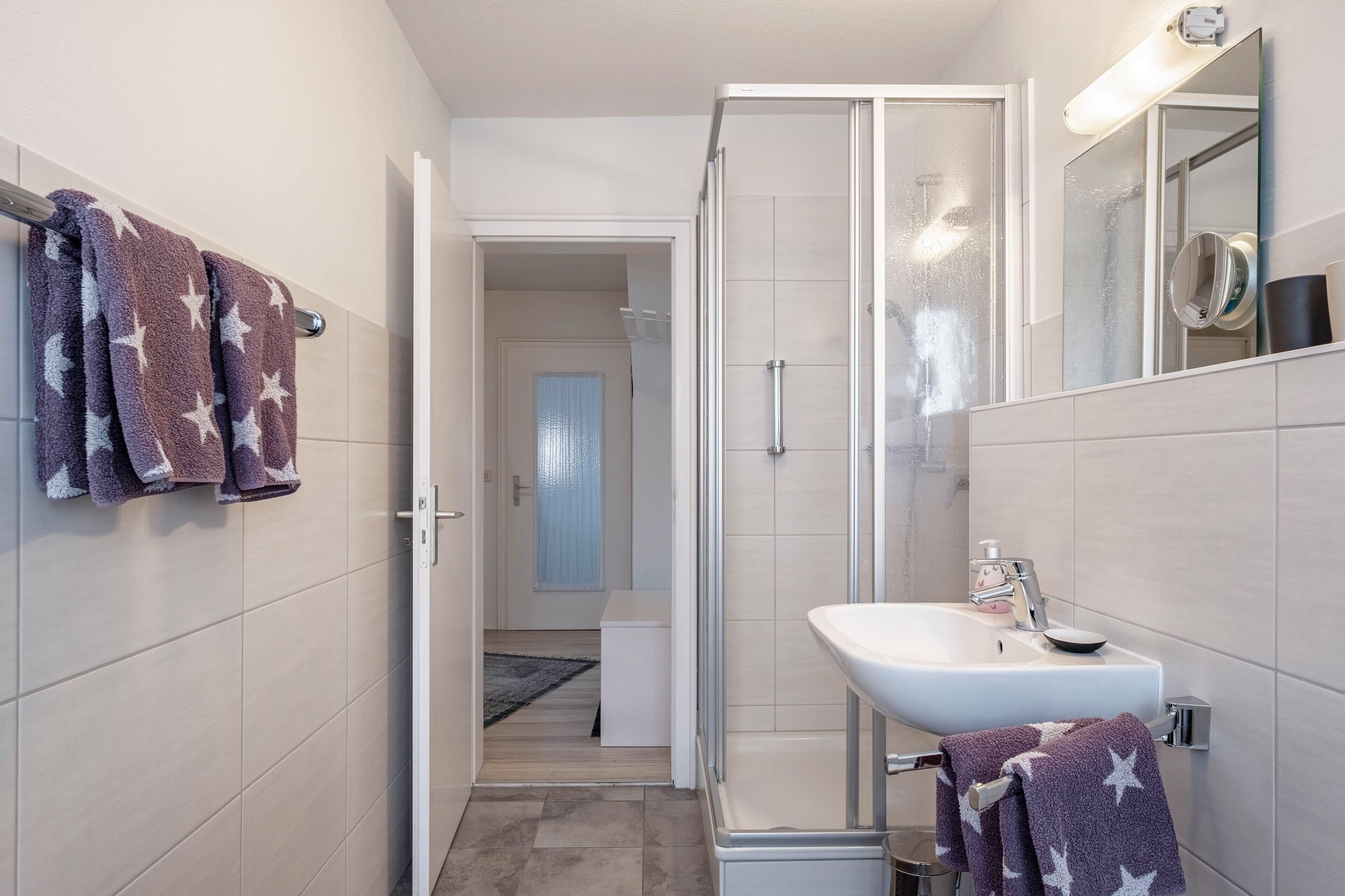 Une salle de bain avec une douche, un lavabo et un porte-serviettes.