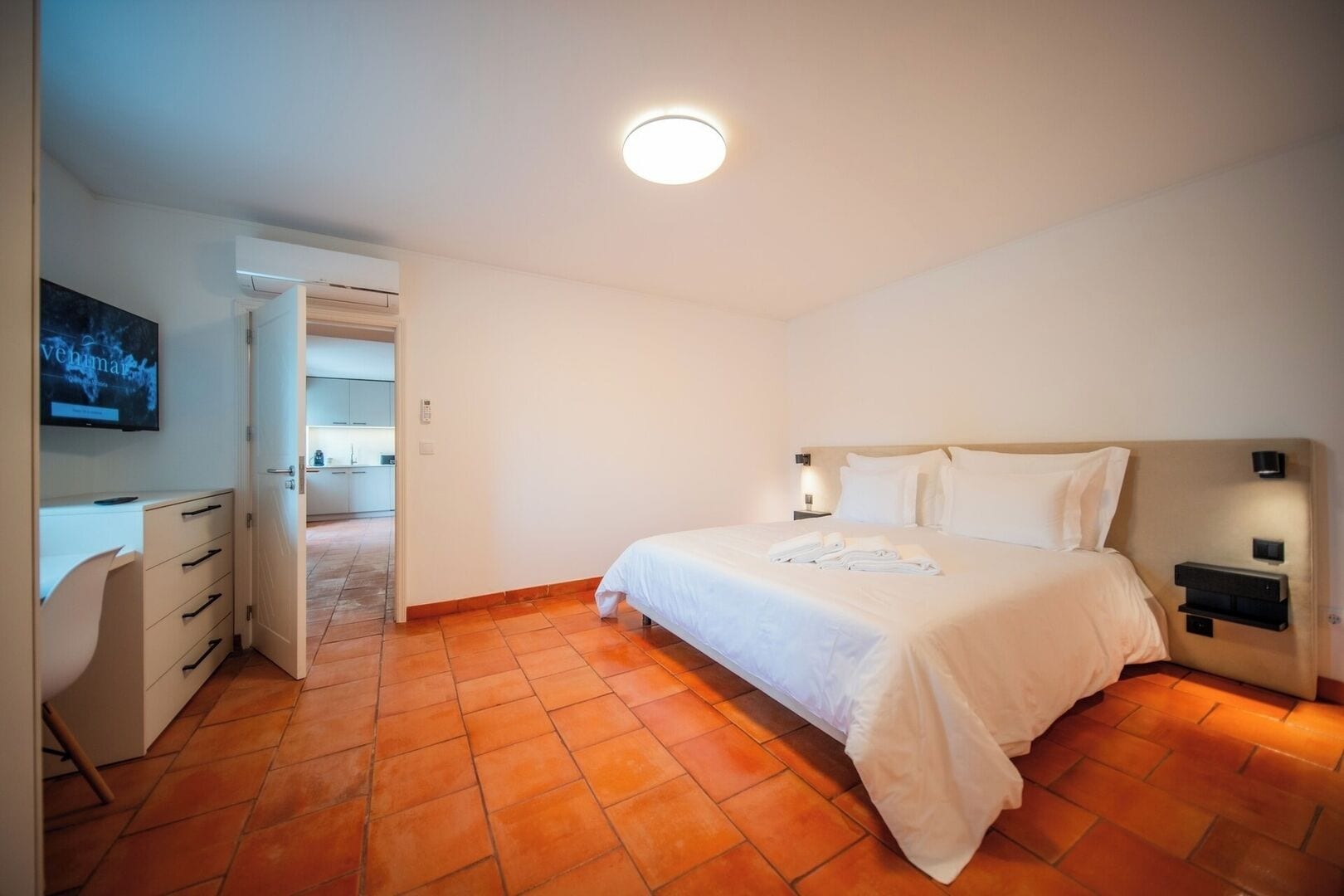 Een slaapkamer met een bed, nachtkastjes, een bureau en een televisie.