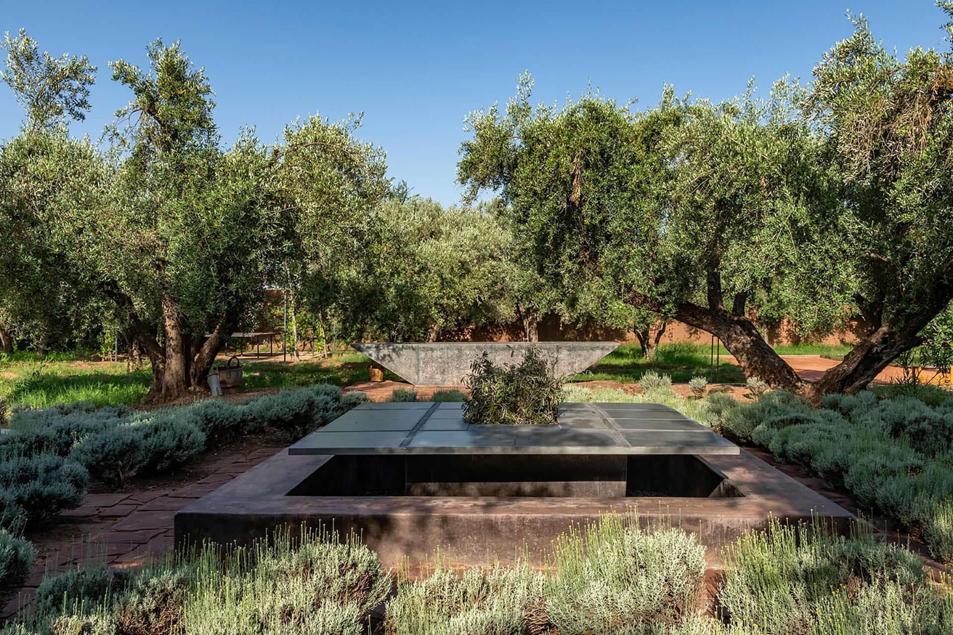 Un área de estar moderna al aire libre con una mesa rectangular y asientos de piedra escalonados y bajos.