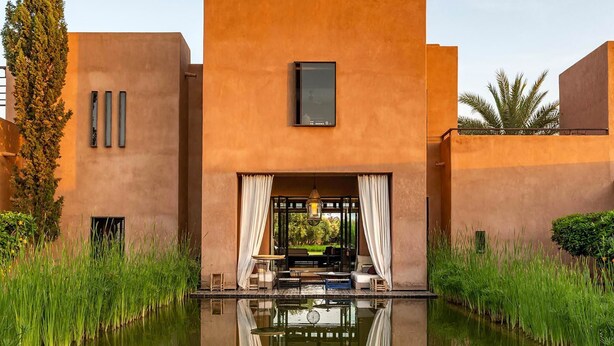 Un bâtiment moderne avec une piscine à l’avant, entouré de verdure.