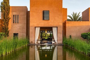 Un bâtiment moderne avec une piscine à l’avant, entouré de verdure.