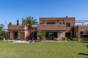 Une maison moderne à deux étages, dotée d’un toit plat, de grandes fenêtres et d’un patio couvert.