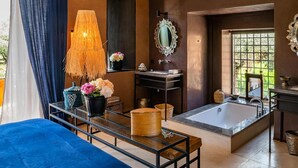 Une salle de bain moderne avec une grande baignoire, un meuble-lavabo en verre et une lampe suspendue.