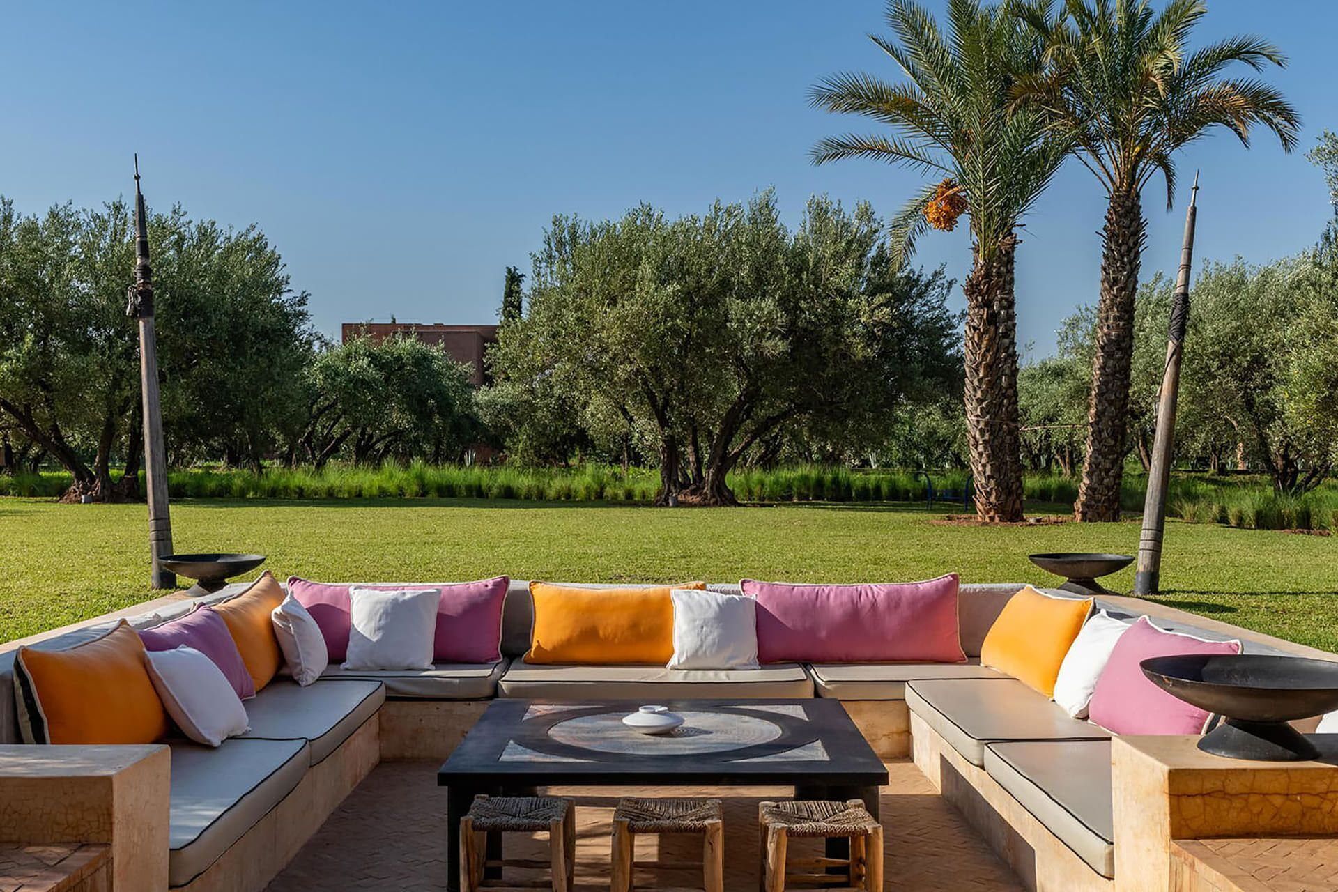 An outdoor seating area with a sofa, cushions, a table, and a bowl.