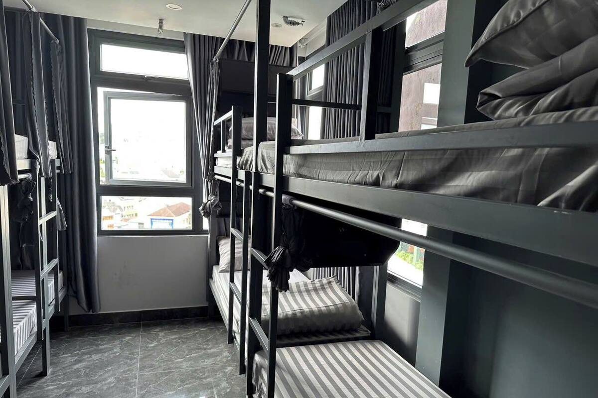 Dormitorio con literas, ventana, cortinas y piso de baldosas.
