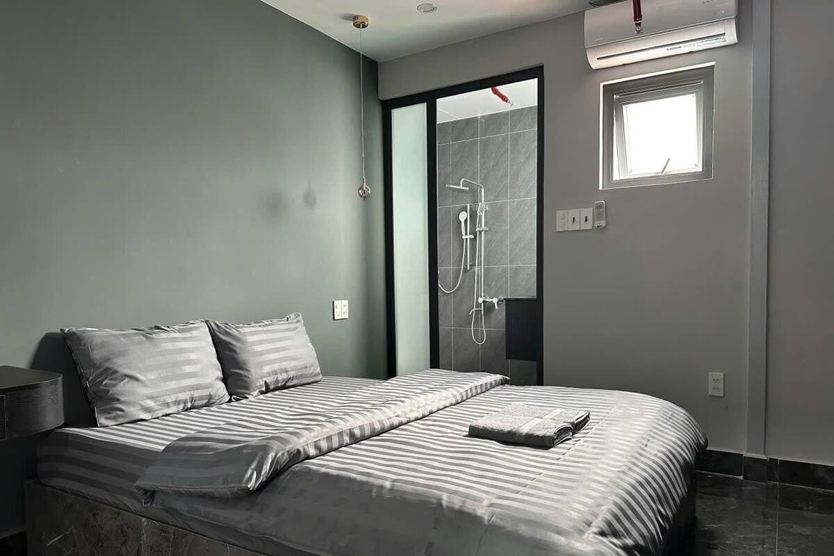 Un dormitorio moderno con una cama grande, ducha integrada y una ventana pequeña.
