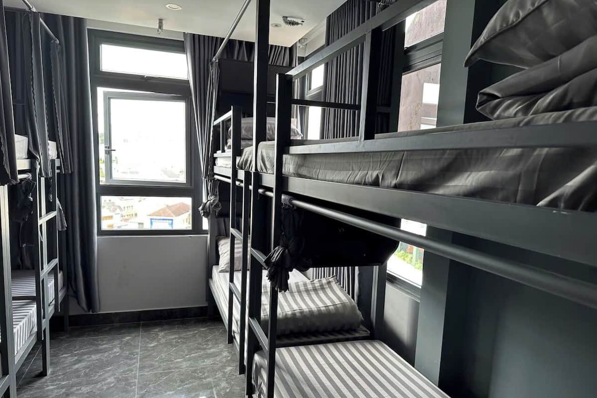 Dormitorio con literas, ventana, cortinas y piso de baldosas.