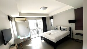 Une chambre d’hôtel moderne équipée d’un grand lit, d’un bureau avec un ordinateur, d’une chaise et d’un téléviseur.