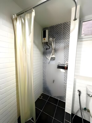 Une salle de bain avec une douche, des murs recouverts de carreaux blancs, un mur avec un motif noir et blanc, et des toilettes.