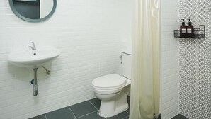 Un baño con lavamanos, inodoro y cortina de ducha blancos.