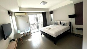 Una habitación de hotel moderna con cama, escritorio, silla, televisor y balcón con vistas.