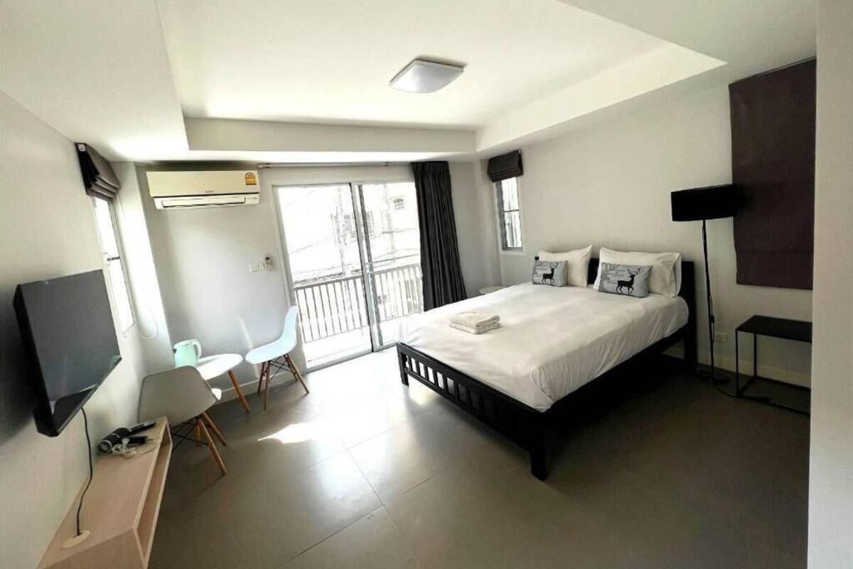 A modern hotel room with a bed, a desk, a chair, a TV, and a balcony with a view.
