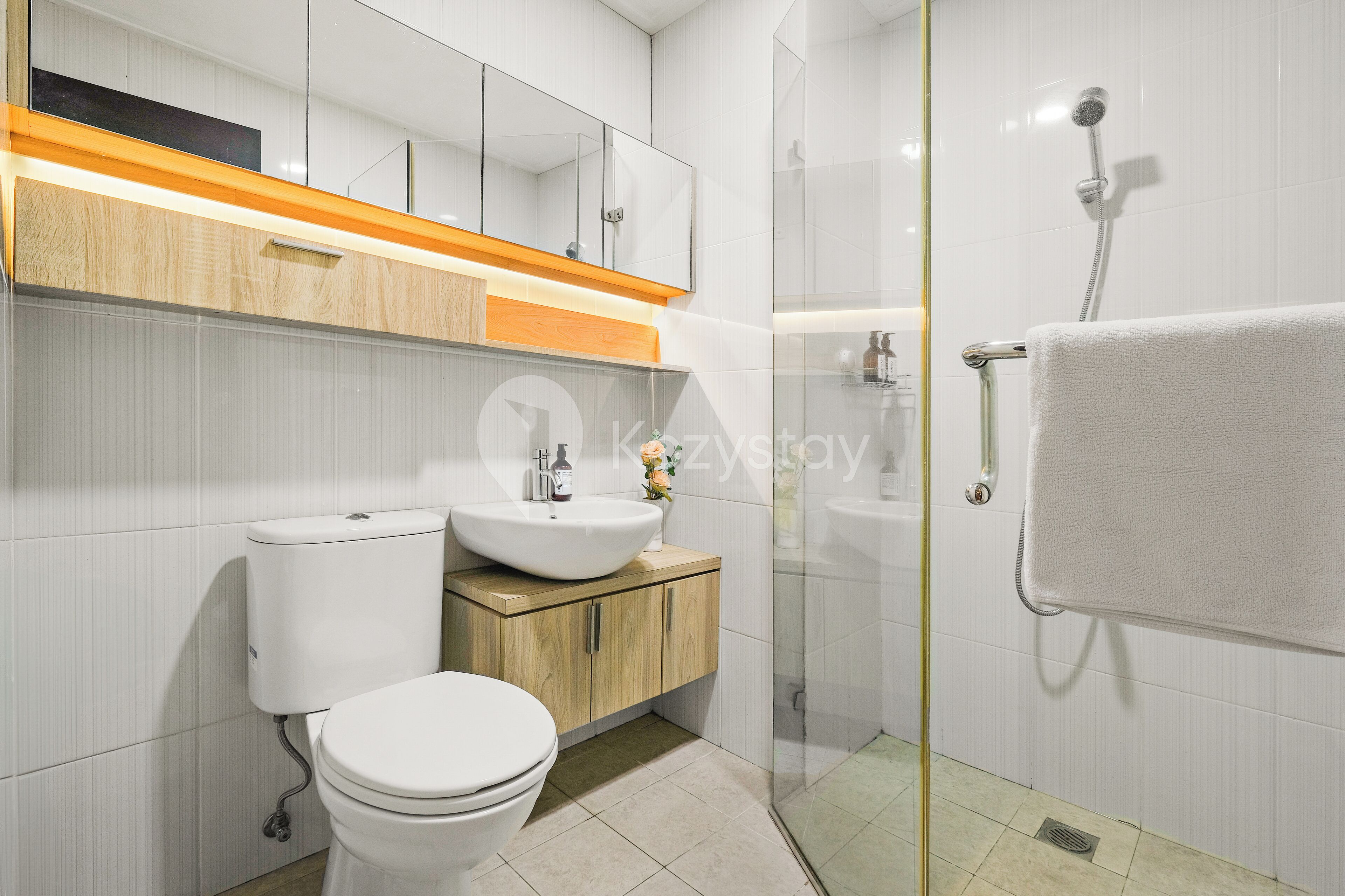 Un baño moderno con inodoro, lavamanos y cabina de ducha de vidrio.