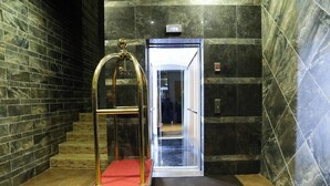 A modern elevator with a glass door, a red carpet, and a marble wall. - Network Hotel and Suites (Ilesa)