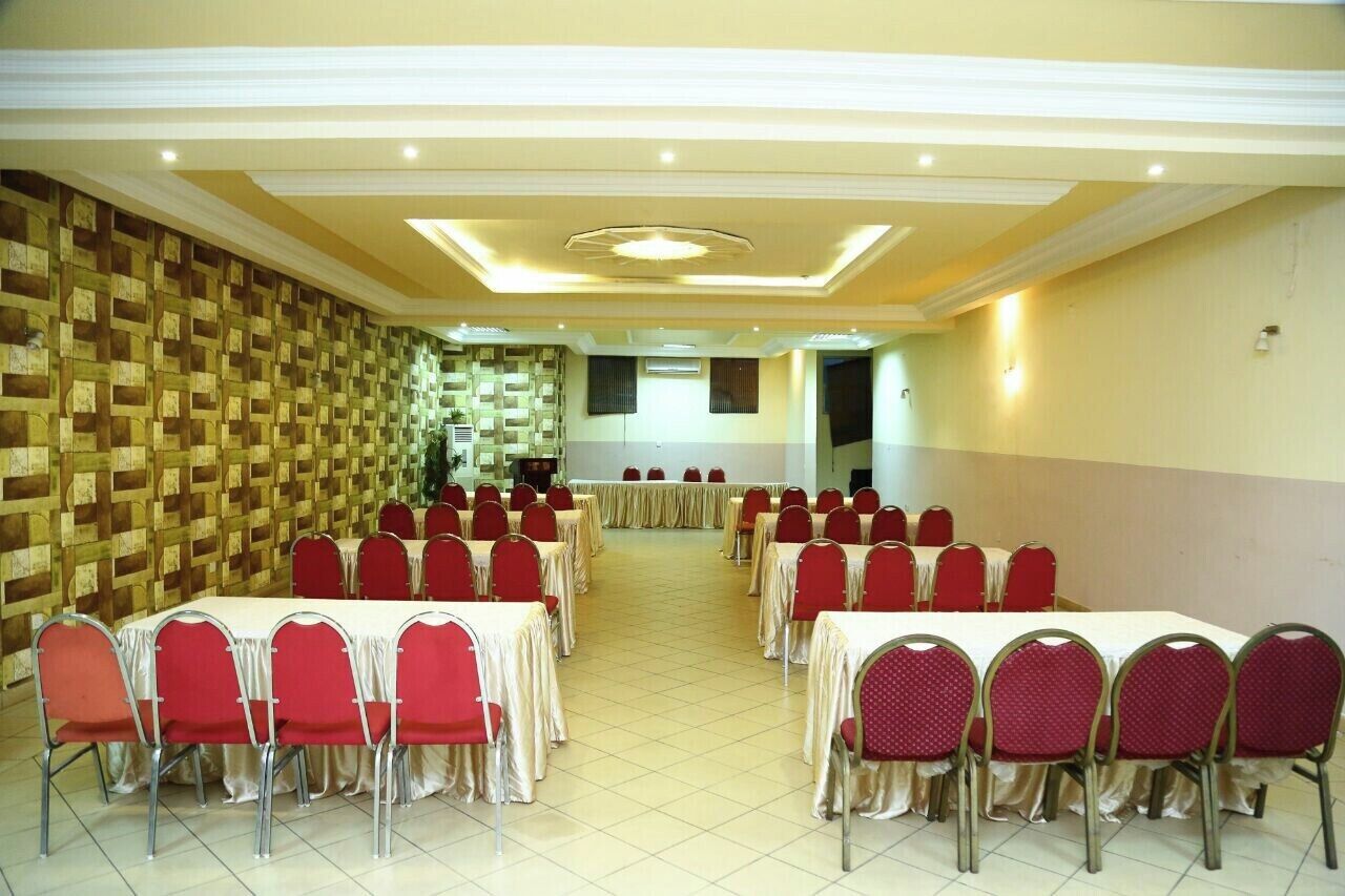 Una sala conferenze con sedie e tavoli rossi, una parete decorata e illuminazione a incasso.