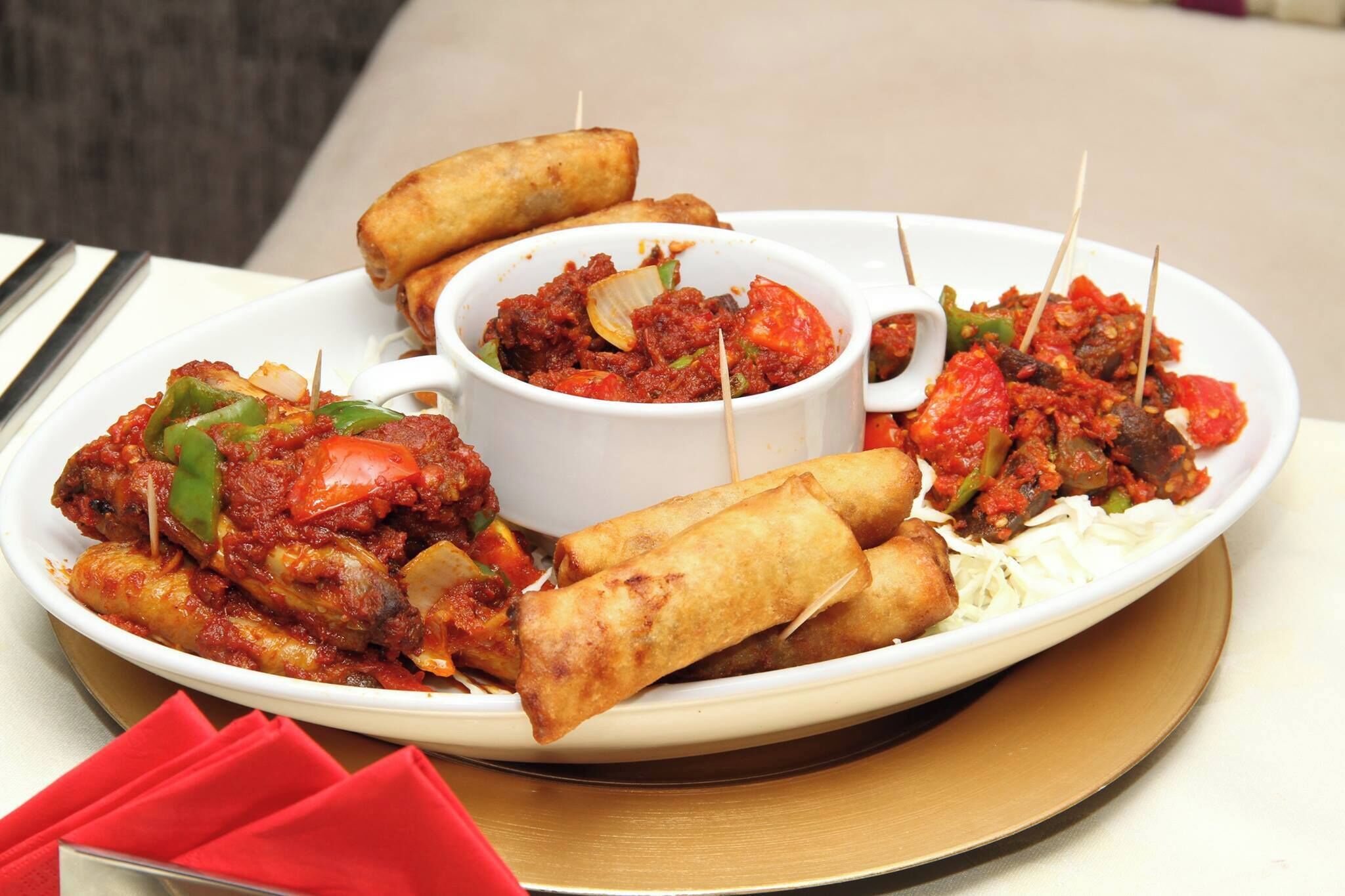 A plate of food including spring rolls, a bowl of sauce, and fried items.