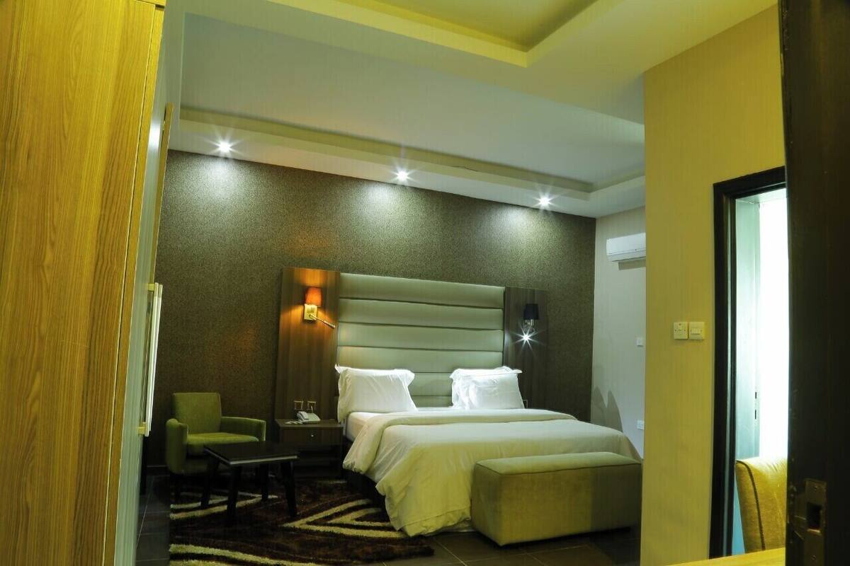 A hotel room with a large bed, a nightstand, a chair, and a small table.