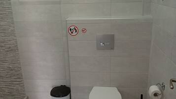 A small bathroom with a toilet, bidet, and a trash bin.