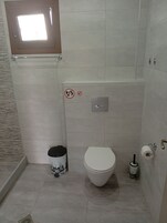 A small bathroom with a toilet, bidet, and a trash bin.