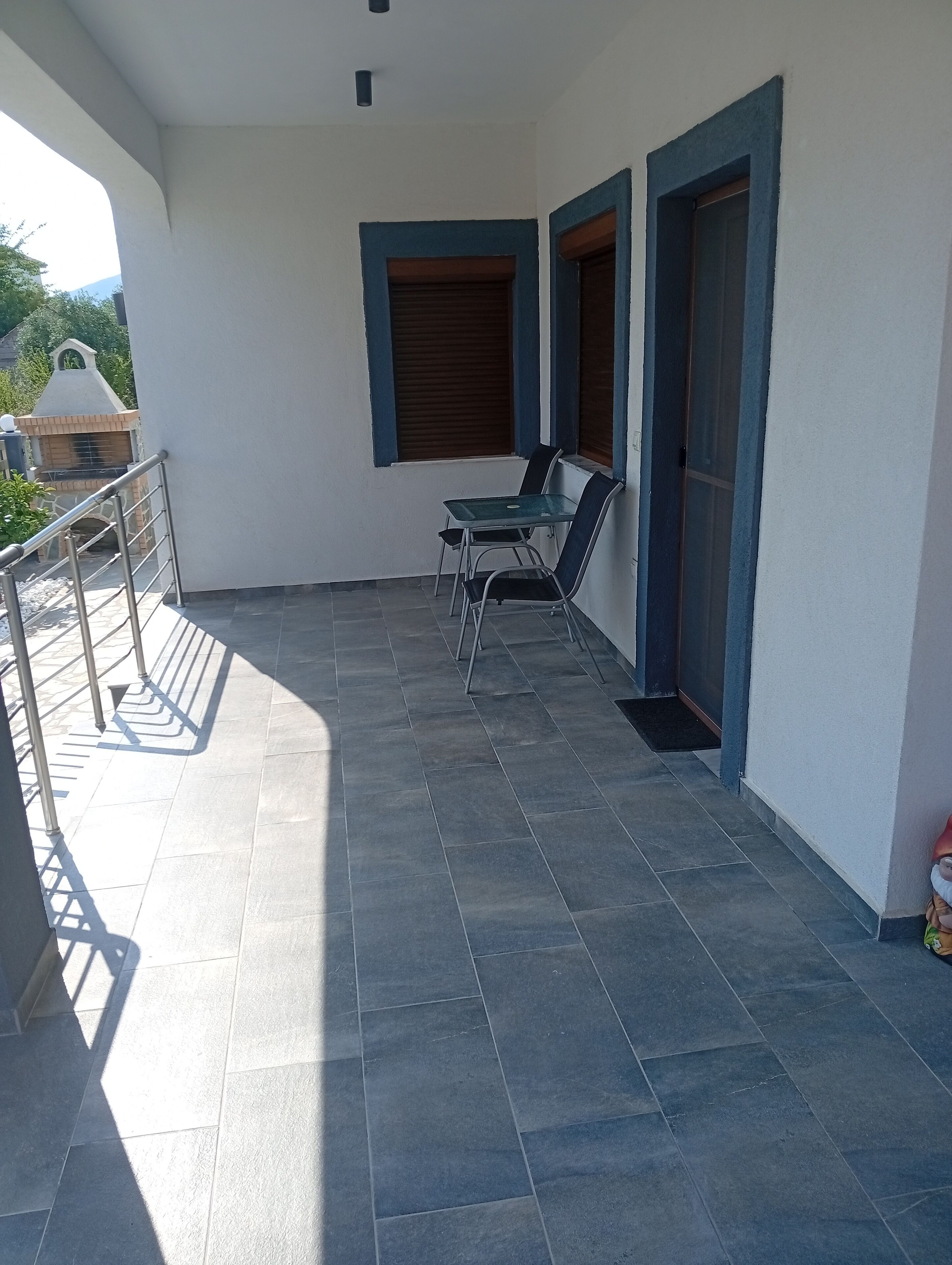 Un balcon avec un sol carrelé, une rambarde en métal et deux chaises.