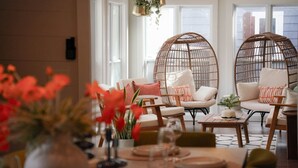 A dining area with wicker chairs, a table set for four, and a vase of red flowers. - Savannah Retreat|Htd Pool|Pickleball|Hot tb|Golf (Savannah)