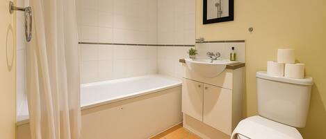 A bathroom with a bathtub, sink, toilet, and a shower curtain.