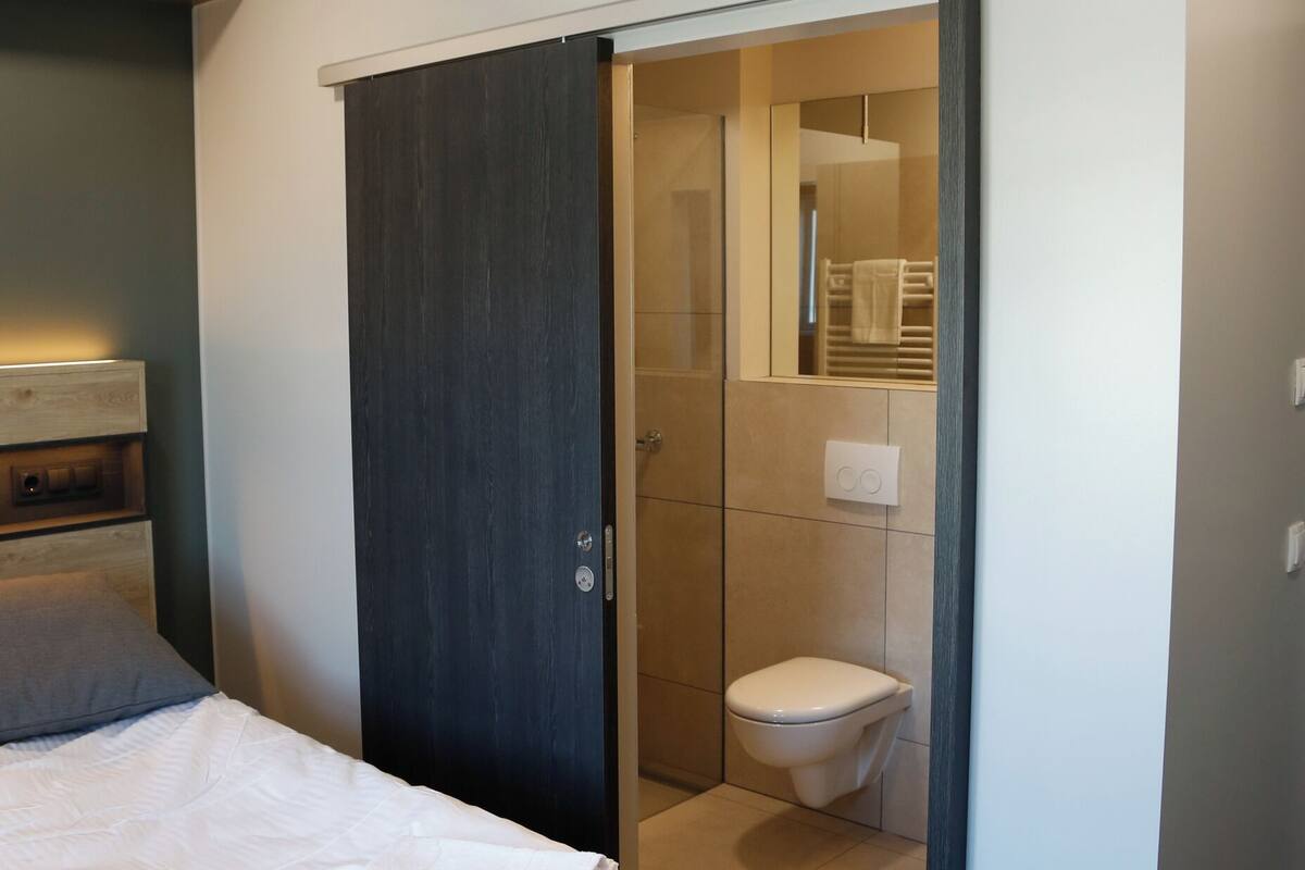 A bedroom with a bed, a wardrobe, and a bathroom visible through an open door.