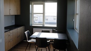 A compact kitchen with wooden cabinets, a black countertop, and a window with a view of buildings outside.