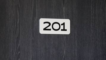 A white sign with the number 201 on a dark wooden surface.