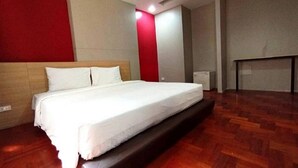 Ein Hotelzimmer mit Bett, Holzboden und einer roten Akzentwand.