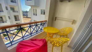 A balcony with a red bean bag chair, yellow chairs, and a small table.