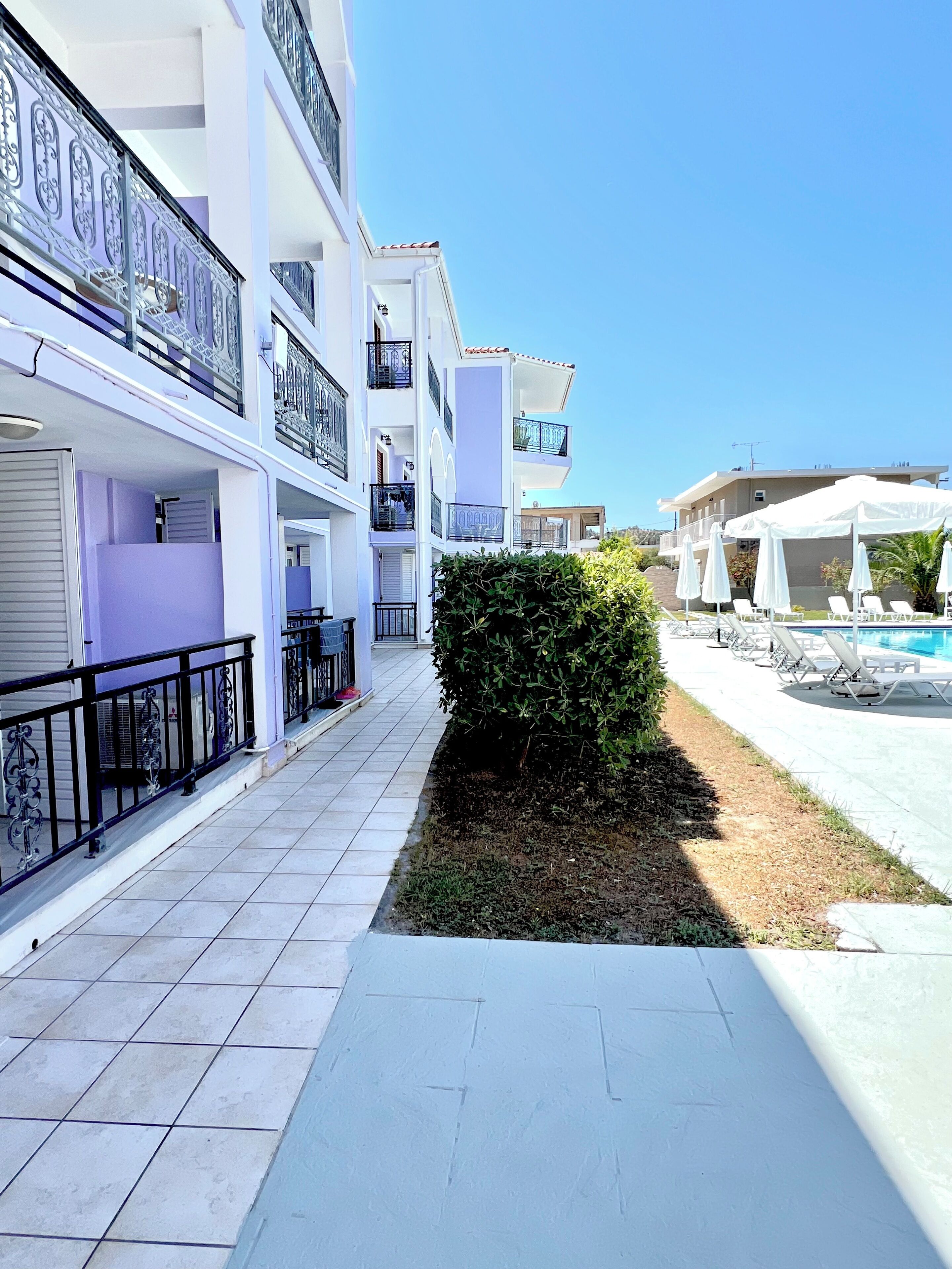 A multi-story hotel with balconies, a swimming pool, and outdoor seating.