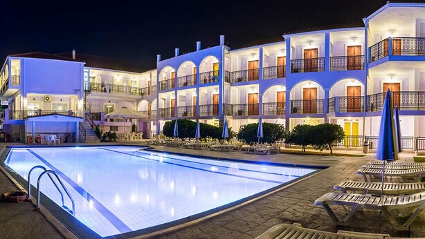 A multi-story hotel with a swimming pool, outdoor seating, and a well-lit facade. - Eleana Hotel by GHH (Zakynthos)