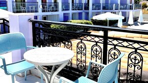 A hotel with multiple balconies, outdoor seating with chairs and a table, and a tiled roof. - Eleana Hotel by GHH (Zakynthos)