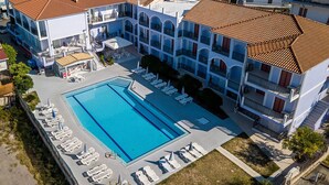 An aerial view of a hotel with a large swimming pool surrounded by lounge chairs and umbrellas. - Eleana Hotel by GHH (Zakynthos)