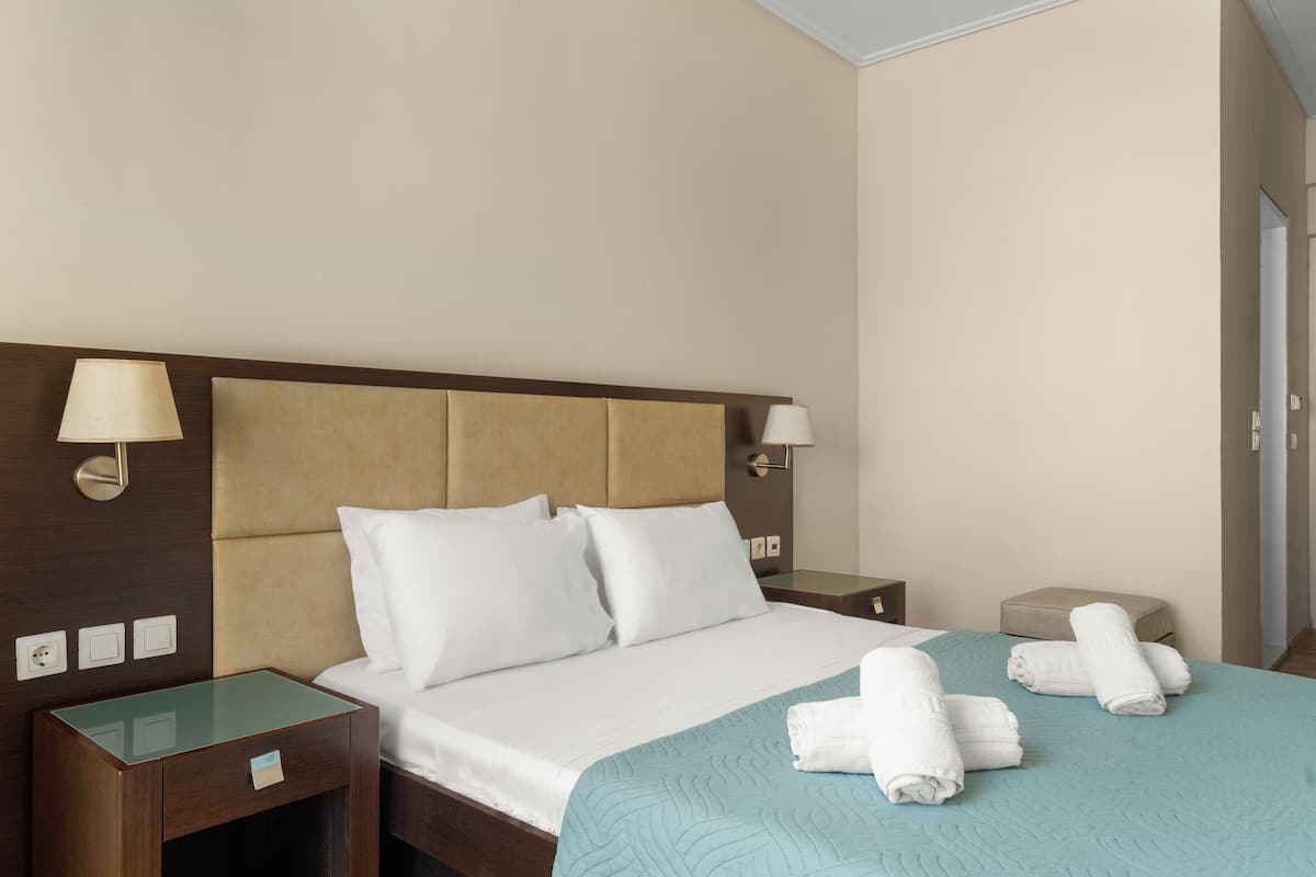 A hotel room with a bed, two bedside lamps, a nightstand, and a small table.