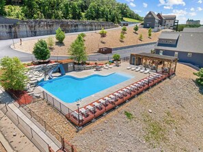 A swimming pool with lounge chairs, a covered seating area, and a small waterfall feature.